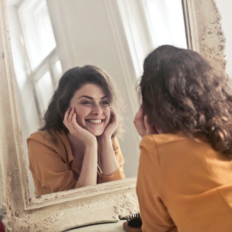 Smiling woman looking at her reflection in a mirror
