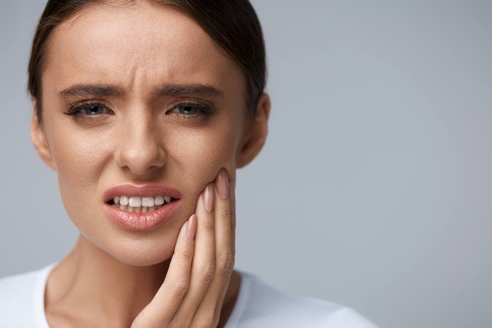 Woman holding her cheek because of dental pain