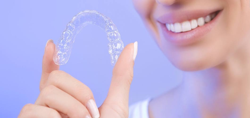Woman holding a clear orthodontic aligner